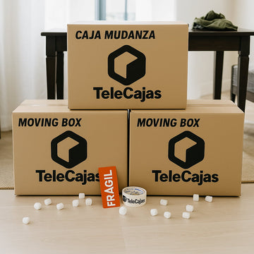Tres cajas de mudanza TeleCajas apiladas, con logo negro visible; delante, cinta adhesiva de la marca, cartel “Frágil” y relleno blanco sobre suelo claro.